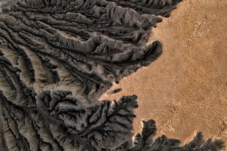 Drone capture of a barren, eroded geological formation in a desert, showcasing dramatic textures.